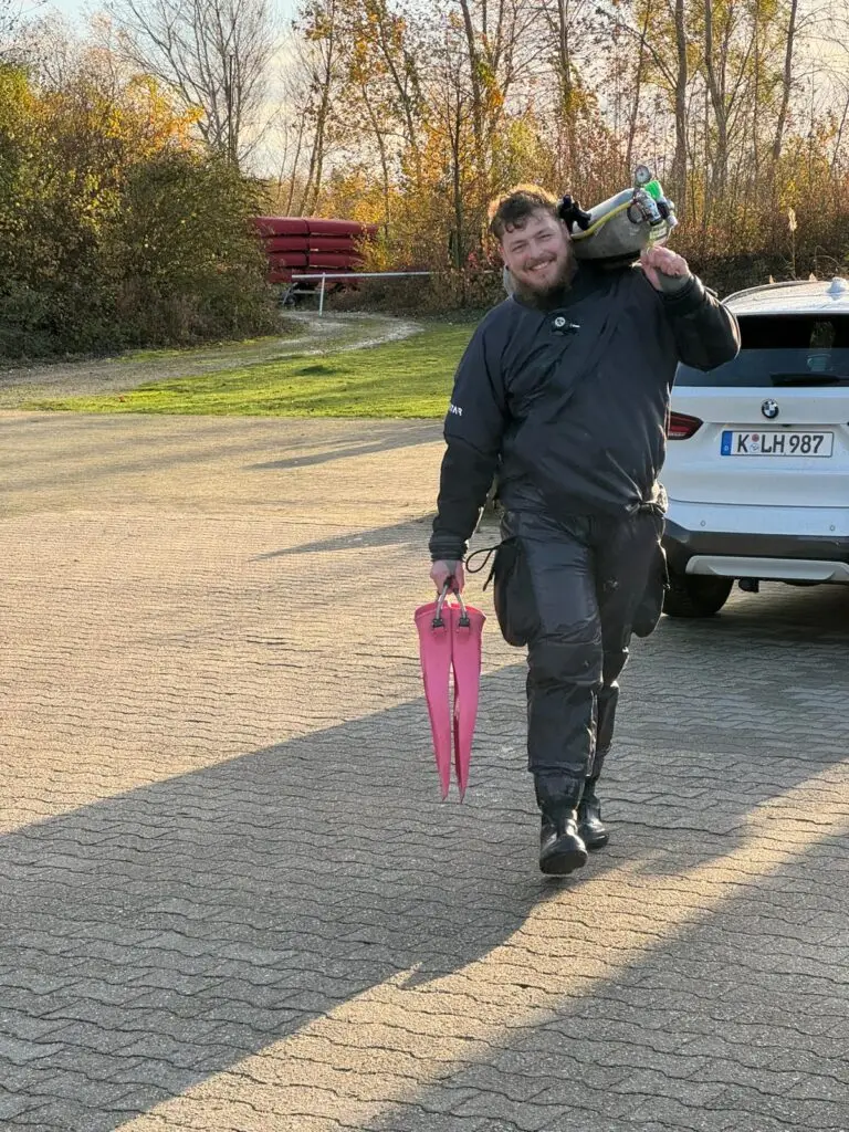 Mann mit Tauchflasche auf der Schulter läuft frontal auf die Kamera zu